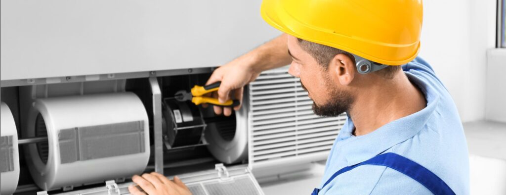 Worker performing preventative maintenance on HVAC air filtration system