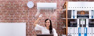 Person turning on air conditioner mounted on brick wall